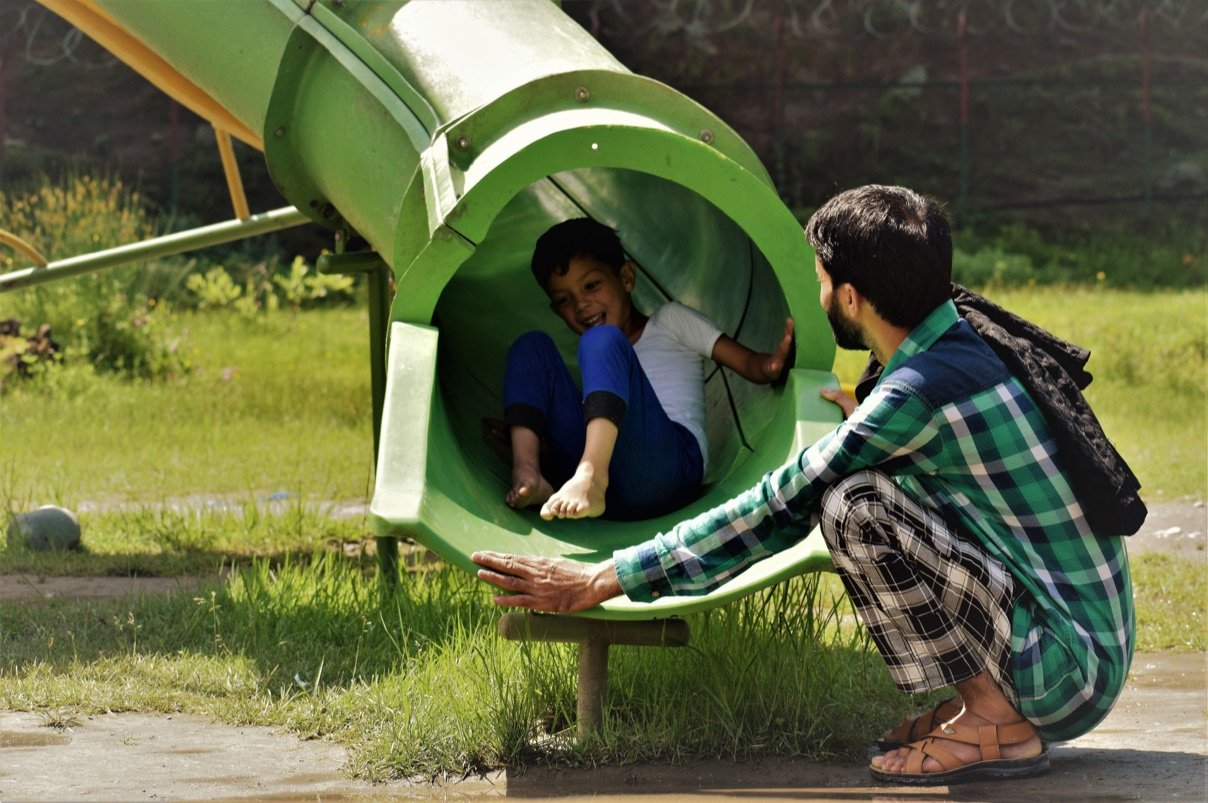Papá y niño jugando dentro de un túnel en un parque infantil de Ingeniarte