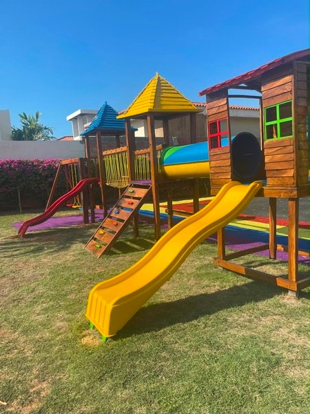 Parque infantil colorido con tobogán amarillo sobre césped instalado por Ingeniarte